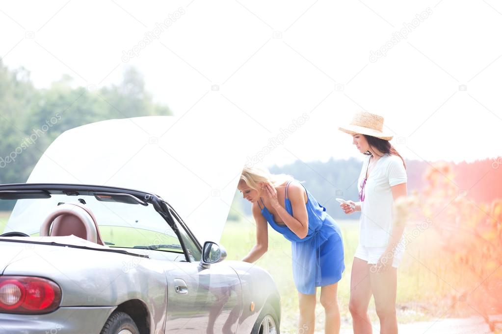 friends examining broken down car
