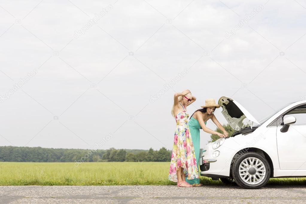 Friends examining broken down car