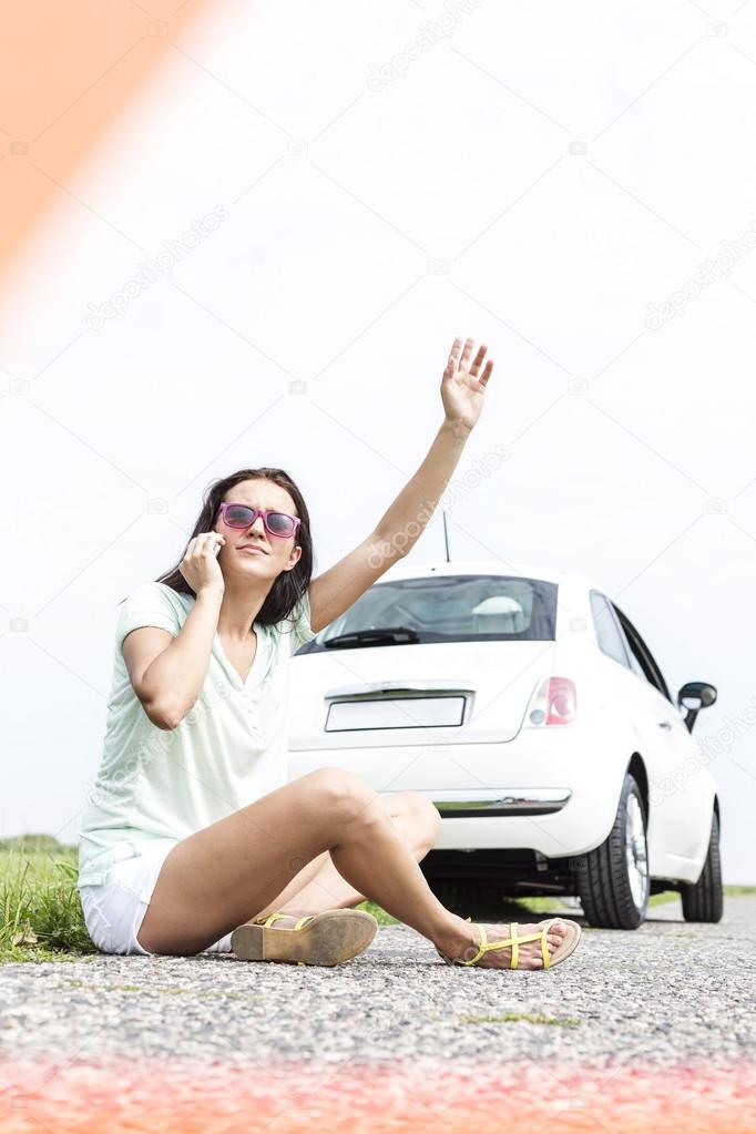 woman hitchhiking while using cell phone