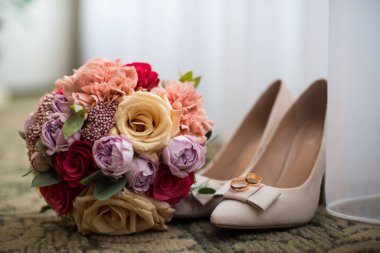 Altın alyanslar güzel bir kompozisyonda ve düğün buketi var.