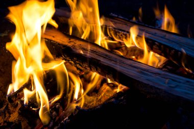 Ateşin sarı alevleri, gecenin karanlığında yanan odun.