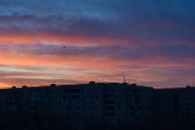 Orenburg şehrindeki çok katlı bir binanın üzerinde çok renkli bir gün batımı.