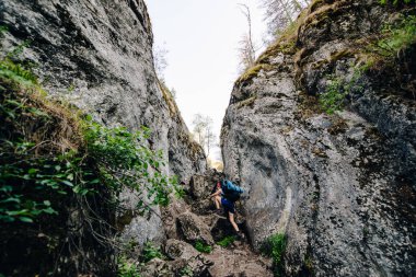 Büyük sırt çantalı bir turist kız kayalara tırmanıyor.