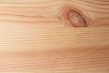 Macro photo of natural wood surface showing grain patterns and knot detail.