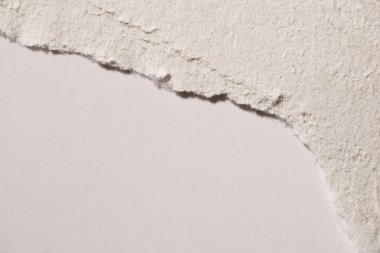 Beyaz bir arkaplan üzerinde yırtılmış lifli beyaz bir el yapımı kağıdının makro görünümü, doku karşıtlığını ve pürüzsüz kenarı gösterir.