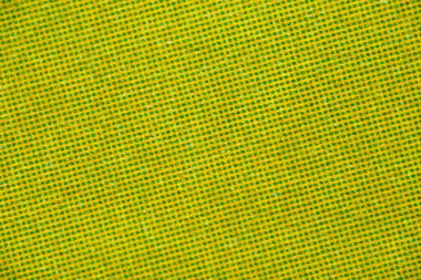 Küçük yeşil yarım ton noktalarla kaplı sarı baskılı kağıdın makro yakın çekimi çapraz bir ızgara oluşturarak parlak desenli soyut bir arkaplan oluşturur..