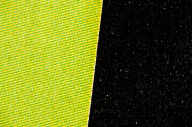 Baskılı kağıdın makrosu, sarı-yeşil yarım tonlu çizgiler ve katı siyah desenli mürekkep arasında keskin bir dikey kenara bölünerek kalın bir grafik karşıtlığı oluşturur..