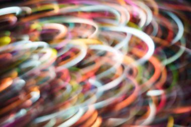 Kıvrımlı kıvrımlı patikaları ve koyu bir arka planda yumuşak hareket bulanıklığı olan canlı çok renkli neon ışık girdapları. Teknoloji, müzik, gece hayatı ve modern tasarım için enerjik soyut arkaplan.