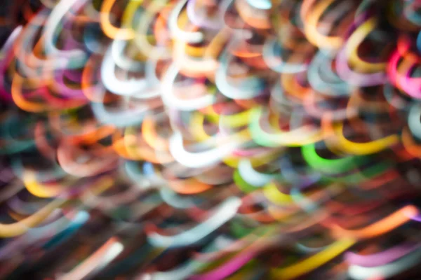 Çok renkli parlak kıvrımlar ve kıvrımlı yollar koyu bir arka planda hafif hareket bulanıklığı. Müzik, gece hayatı, teknoloji ve modern yaratıcı tasarımlar için enerjik soyut arkaplan.