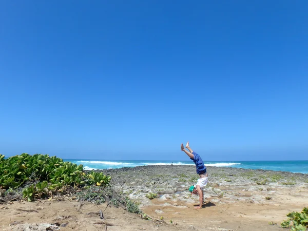 Hombre de pie en las rocas de coral en la playa como choque de olas en th —  Fotos de Stock