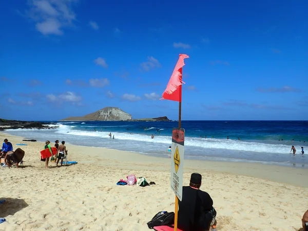 La gente juega en la playa con un fuerte cartel actual en la playa —  Fotos de Stock