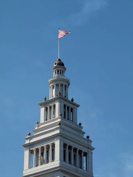 上部の風の中の旗波フェリービルディングクロックタワーサンフランシスコのウォーターフロントのランドマークであり 1898年に完成しました — ストック写真
