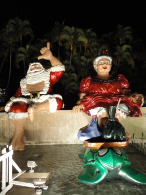 Honolulu, Hawaii - 5 Aralık 2010: Bay ve Bayan Noel Baba ellerinde hindistan cevizi içeceği, poi poşeti ve Lau Lau Light ile birlikte Honolulu Belediye Başkanı Hale 'in önünde Honolulu City Lights' ın bir parçası olarak şelalede oturuyorlar. 