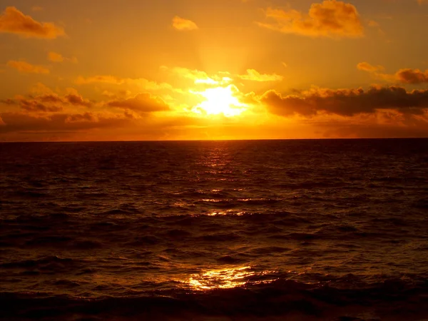 波状の水の上の雲の間からの日の出ハワイ州オアフ島のワイマナロ湾 — ストック写真