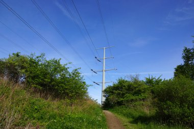 Metal elektrik direğinden ile Hill'de distan yukarı giden toprak yol