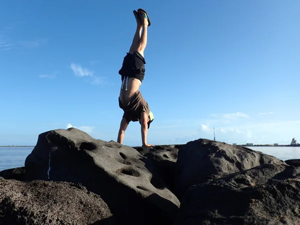 Man Handstands on rock jetty in Kahului Harbor — Stock Photo, Image