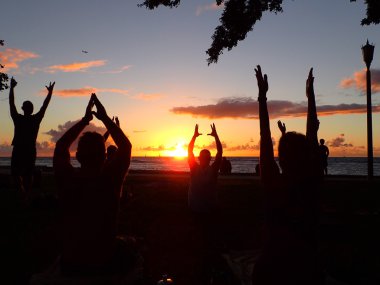 İnsanlar uçak ile Waikiki Beach sadaka için günbatımı yoga yapmak
