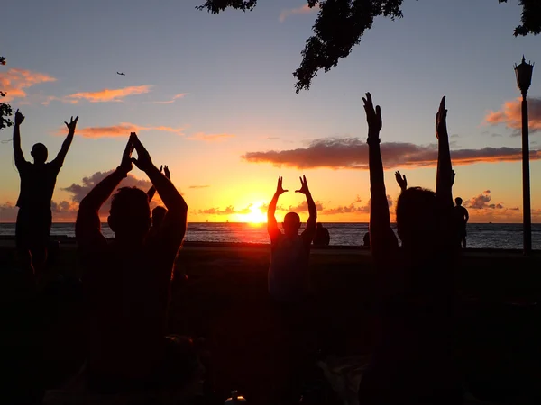 Menschen machen Sonnenuntergang-Yoga für den guten Zweck am Strand von Waikiki mit Flugzeug in — Stockfoto