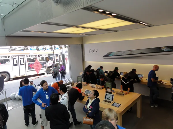 Leute schauen sich Produkte an und sprechen mit Verkaufsmitarbeitern im Apple Store — Stockfoto