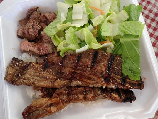 Filete, Kalbi, Ensalada lateral y arroz blanco en un plato de espuma de poliestireno — Foto de Stock