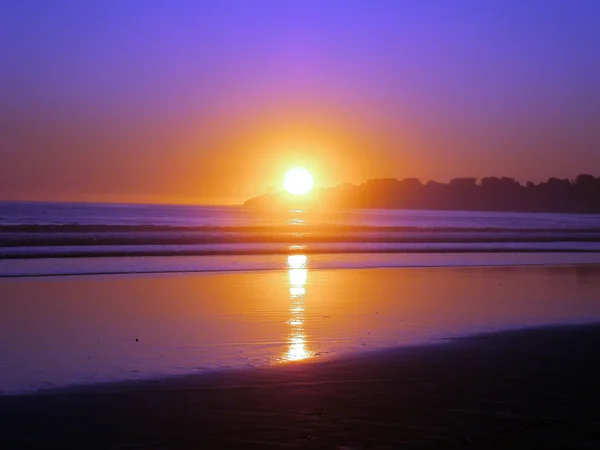 Pôr-do-sol épico reflete no oceano e na praia em um céu limpo vazio da — Fotografia de Stock