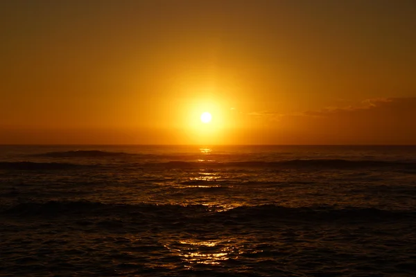 Lever de soleil sur l'océan avec des vagues roulant vers le rivage — Photo