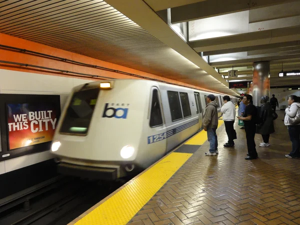 BART Train speeds into station platform with people waiting and — Stock Photo, Image