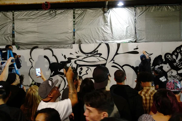 La gente rocía arte de pintura en la pared como otras personas registran la actividad w — Foto de Stock
