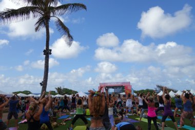 People raise arms over head during outdoor yoga class along the  clipart
