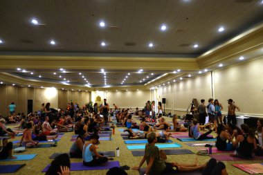 Students talk and gather before the start of large yoga class fe
