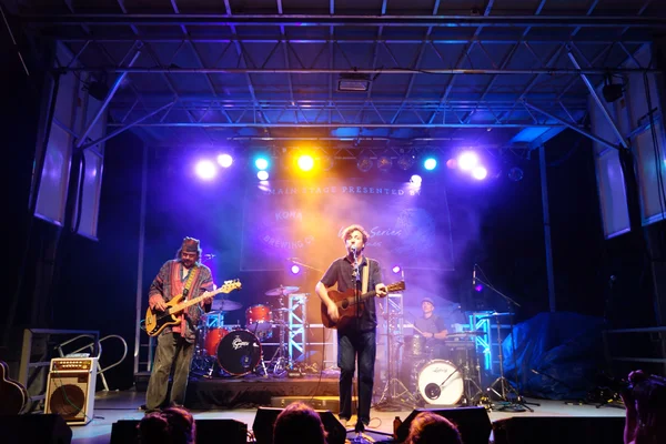 Roothub sings into mic as he performs on stage during a evening — Stock Photo, Image