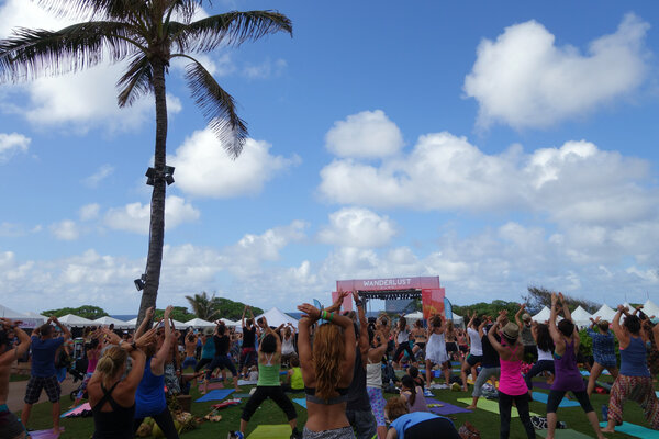 People raise arms over head during outdoor yoga class along the 