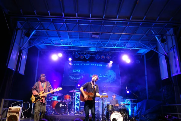 Roothub sings into mic as he performs on stage during a evening — Stock Photo, Image