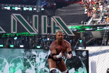 Triple H points at himself as he stands on top of turnbuckles