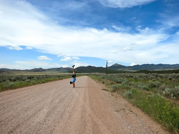 Man wearing a hat, t-shirt, shorts, and slippers does Handstands — Stock fotografie