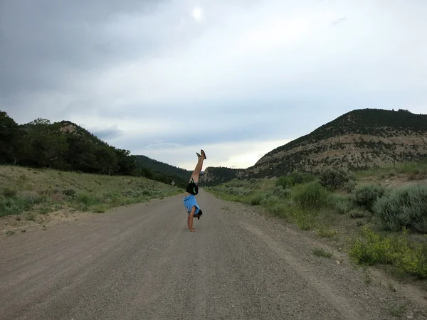 Hombre con sombrero, camiseta, pantalones cortos y zapatillas hace Handstands —  Fotos de Stock