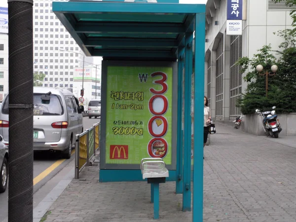 Paragem de ônibus com anúncio mcdonalds na rua movimentada — Fotografia de Stock