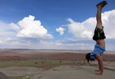 Man does Handstand on cliffs with field landscape 