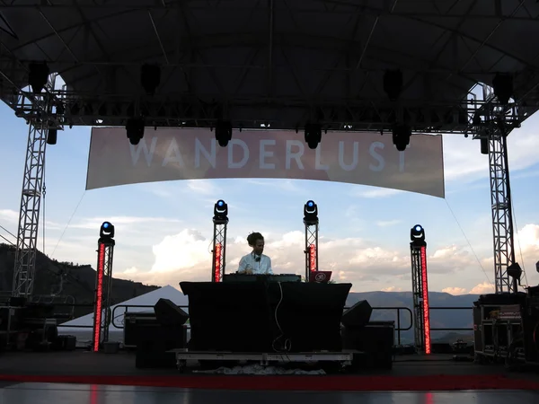 DJ Drez gira no palco durante concerto com paisagem montanhosa — Fotografia de Stock