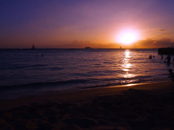 Άνθρωποι που παίζουν στο νερό με το εντυπωσιακό ηλιοβασίλεμα στην παραλία αυτό — Φωτογραφία Αρχείου