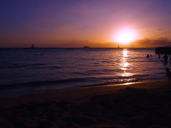 As pessoas brincam na água com o dramático pôr do sol na praia de Kaimana — Fotografia de Stock