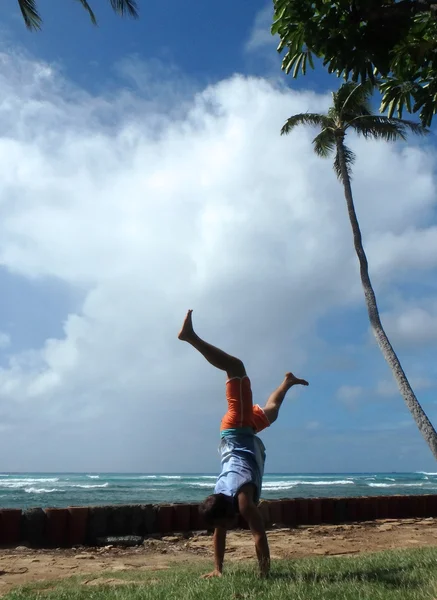 Man Handstanding in the grass along cliff shore next to shallow — Stock Photo, Image