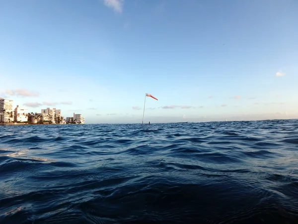 Fahnenmast mit Windsocke ragt über das wellige Wasser — Stockfoto