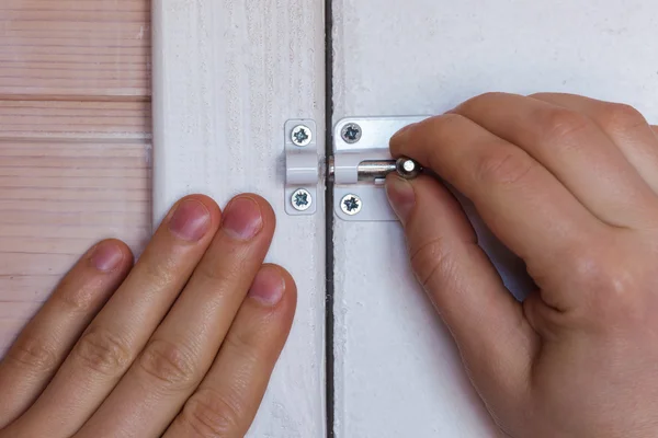 Man closes a small latch. — Stock Photo, Image