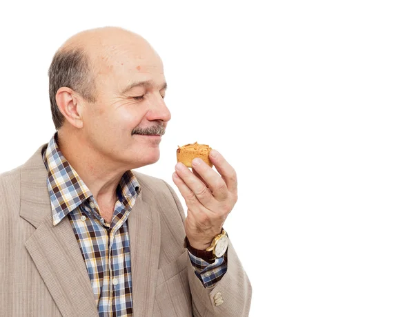 Homem idoso tenta delicioso queque ou cupcake — Fotografia de Stock