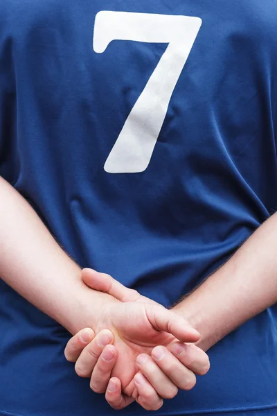 Atleta en uniforme se para con las manos dobladas detrás de su espalda . — Foto de Stock