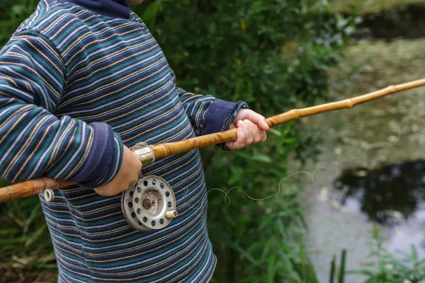 Barnet håller gamla fiskespö i händer — Stockfoto