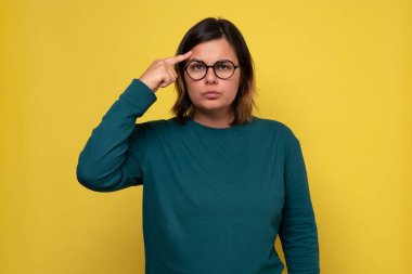 Gözlüklü güzel kadın yarın için planlar yapıyor. İş projesi için fikir üretiyorum. Stüdyo fotoğrafı sarı duvarda..