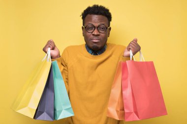 Elinde alışveriş torbaları tutan Afrikalı adam yoruluyor. Alışverişkolik kavram.