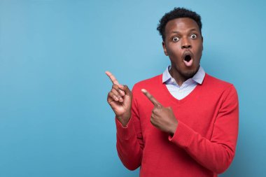 Afro-Amerikalı adam ağzını kocaman açıyor, mavi duvarı işaret ediyor..